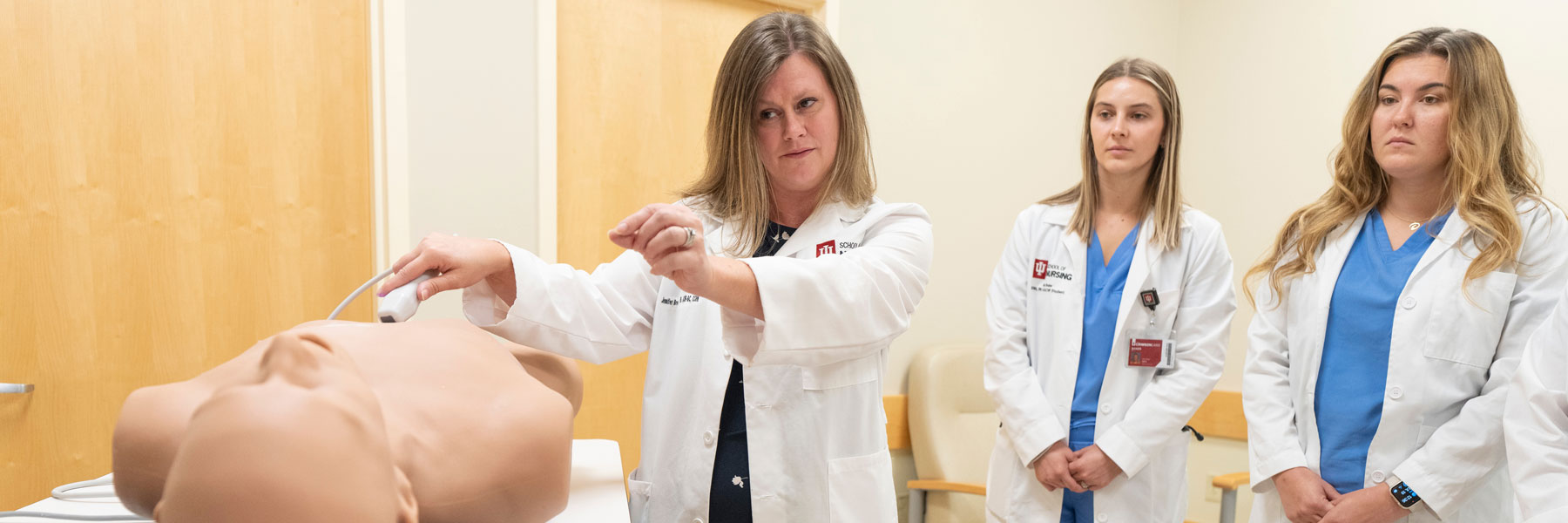 IU School of Nursing graduate students listen to a faculty member during a hands-on lecture.