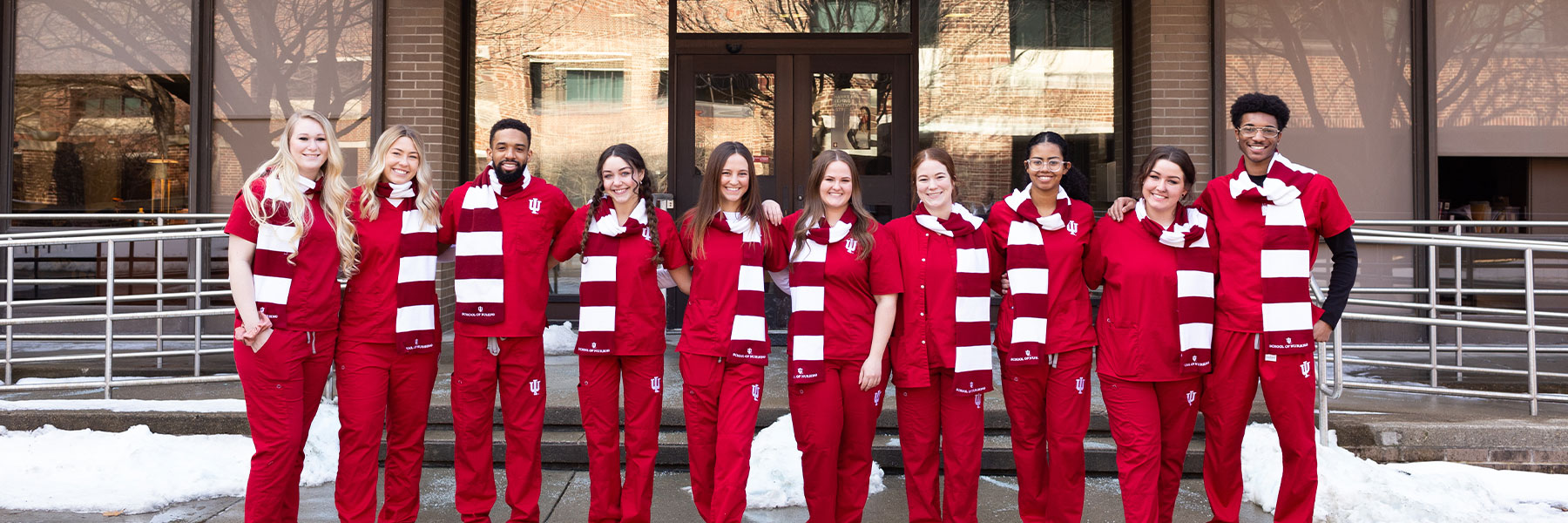 Group of nursing students at IUPUI stand outside the main entrance of the School of Nursing building in scarves