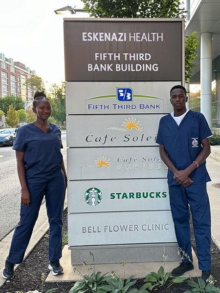 Moi University students Olivia Watta and Victor Kiplagat pose for a photo near an Eskenazi Health sign