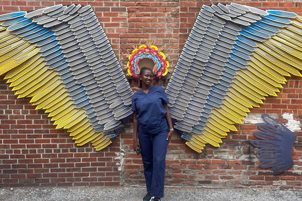 Moi University student Olivia Watta poses with a mural in Fort Wayne