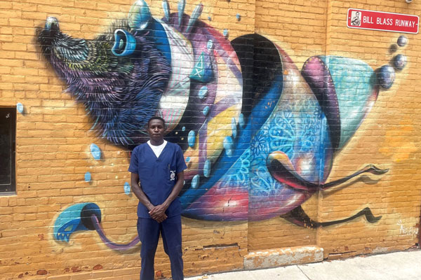 Moi University student Victor Kiplagat poses with a mural in Fort Wayne