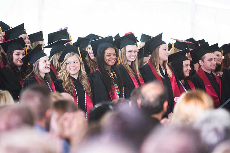 A group of graduates in caps and gowns standing in rows