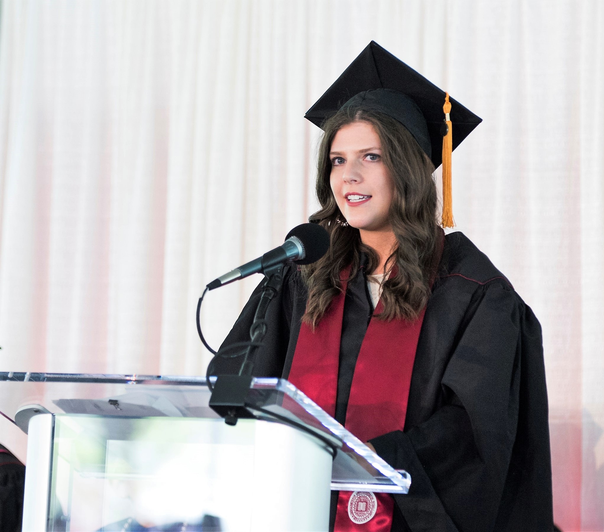 Class president in cap and gown making presentation at podium