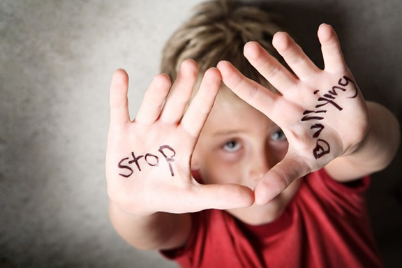 Young boy with outstretched hands containing words "stop bullying" printed on the the palms