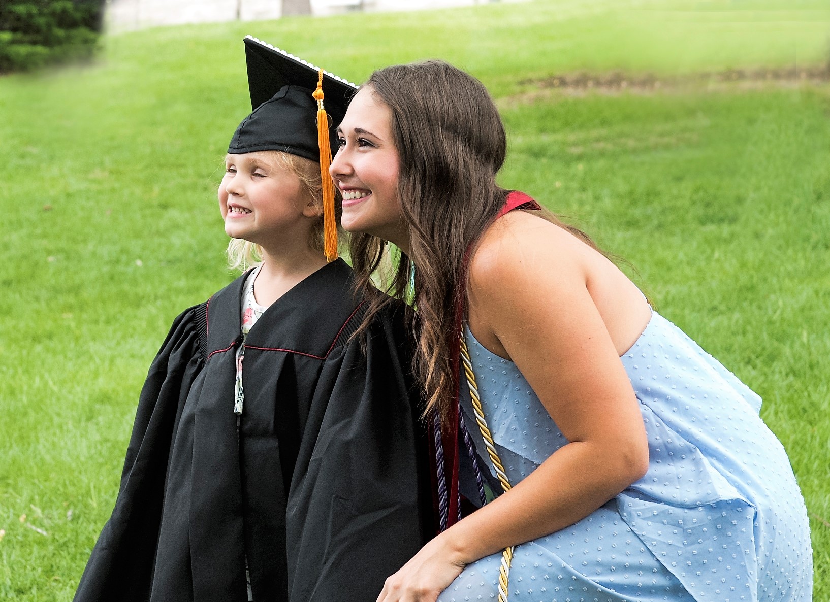 Young woman and little girl wearing mortar board