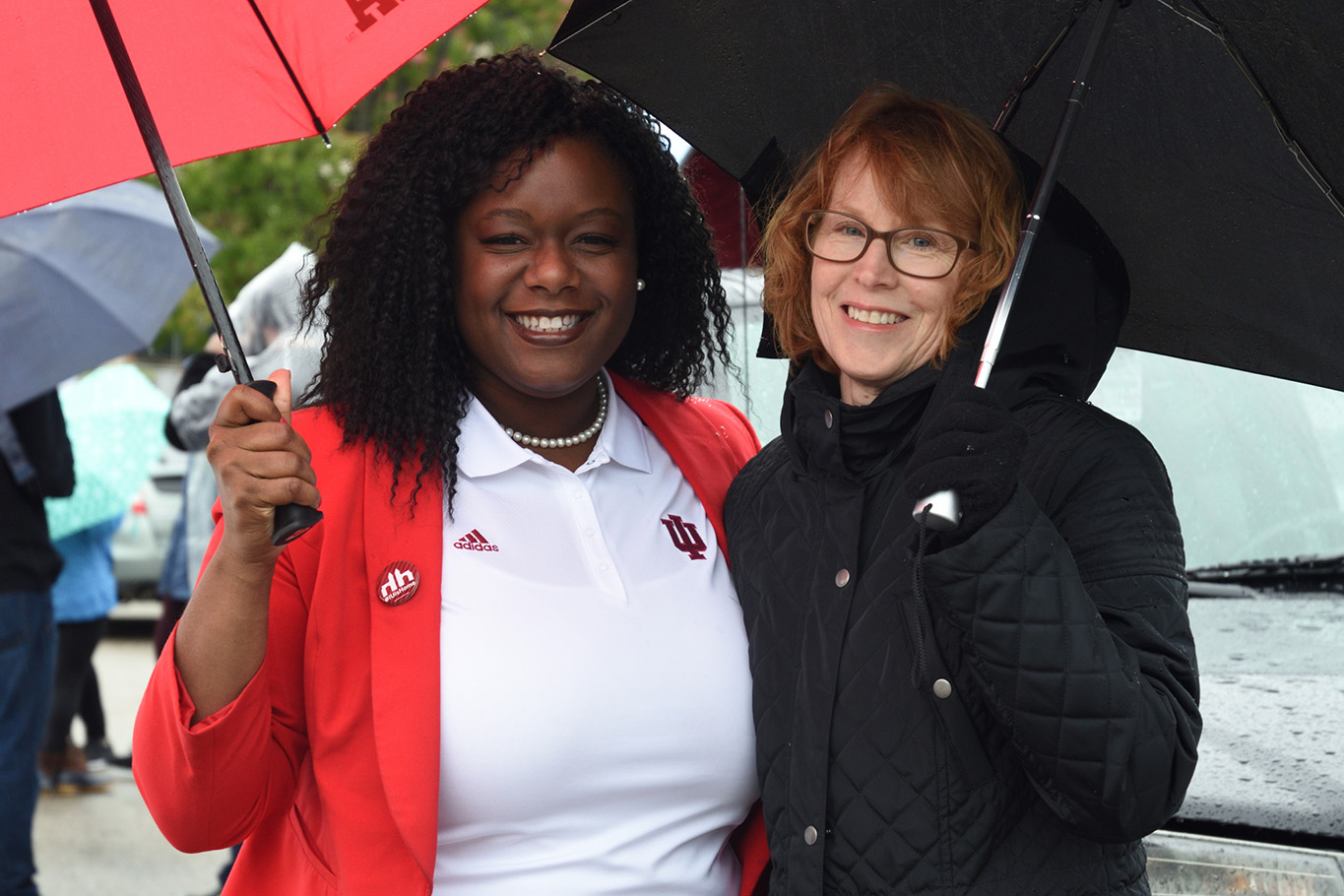 fans holding umbrellas on rainy homecoming parade day