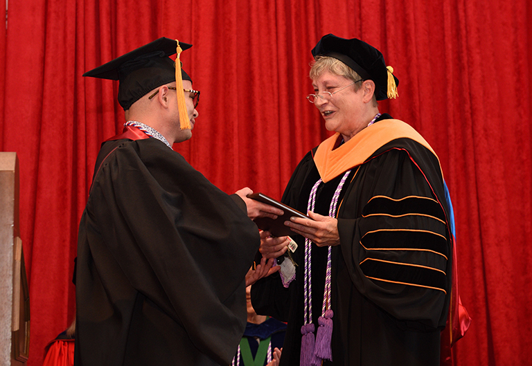 graduate receiving diploma from faculty