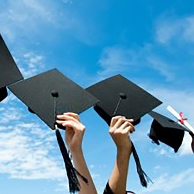 Several mortar boards held up against the blue sky