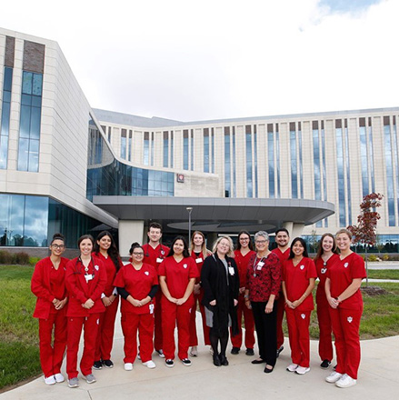 Students in red scrubs standing in front of Regional Academic Health Center