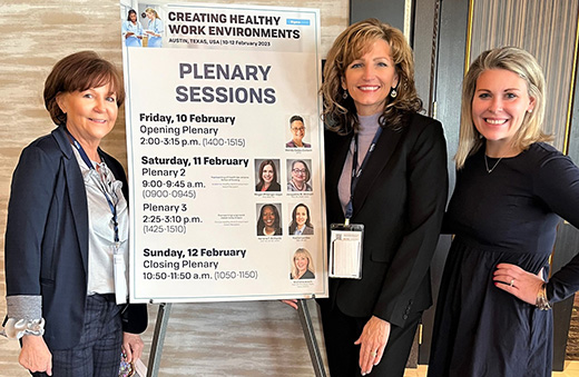 Drs. Sandra Davis, Angela Opsahl and Emily Davis pose near a Sigma Theta Tau International "Creating Healthy Work Environments" sign